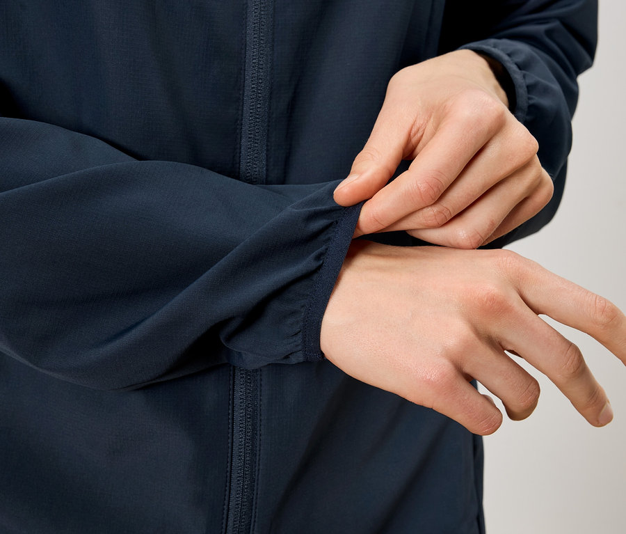 Person zupft am Ärmel einer marineblauen Jacke.