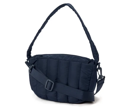 Eine marineblaue, gesteppte Handtasche mit einem verstellbaren Trageriemen liegt auf einem weißen Hintergrund.