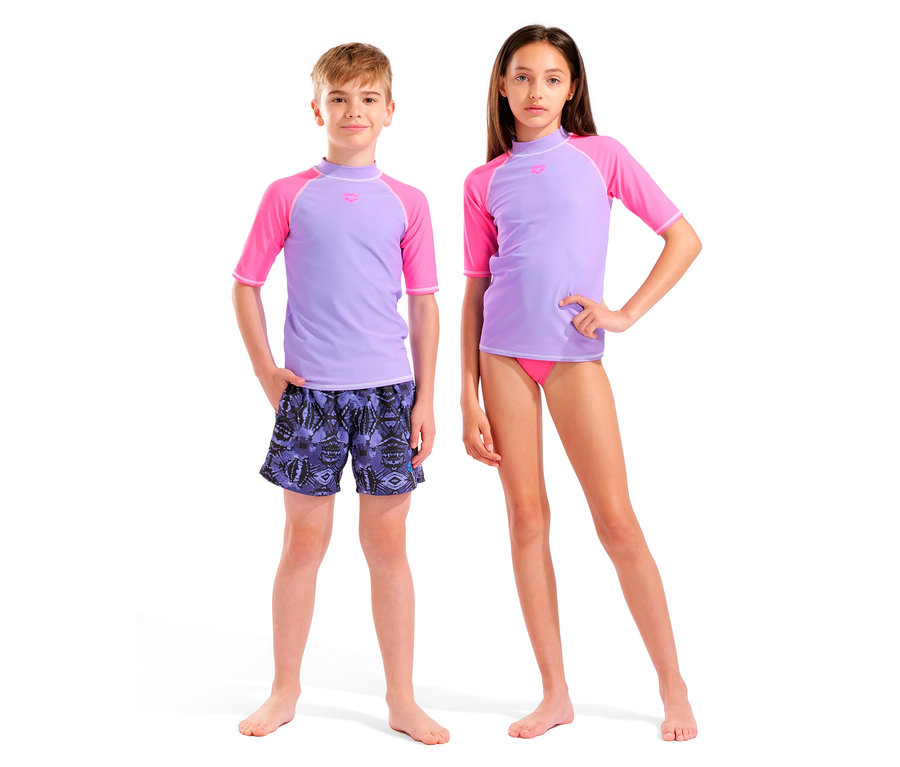 Ein Junge mit lila-pinkem Kurzarm-Badeoberteil und gemusterten Badeshorts steht neben einem Mädchen mit lila-pinkem Kurzarm-Badeoberteil und pinker Badehose.