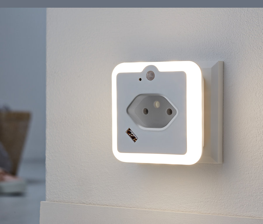 Ein weißes LED-Nachtlicht ist in eine Steckdose an einer Wand gesteckt.