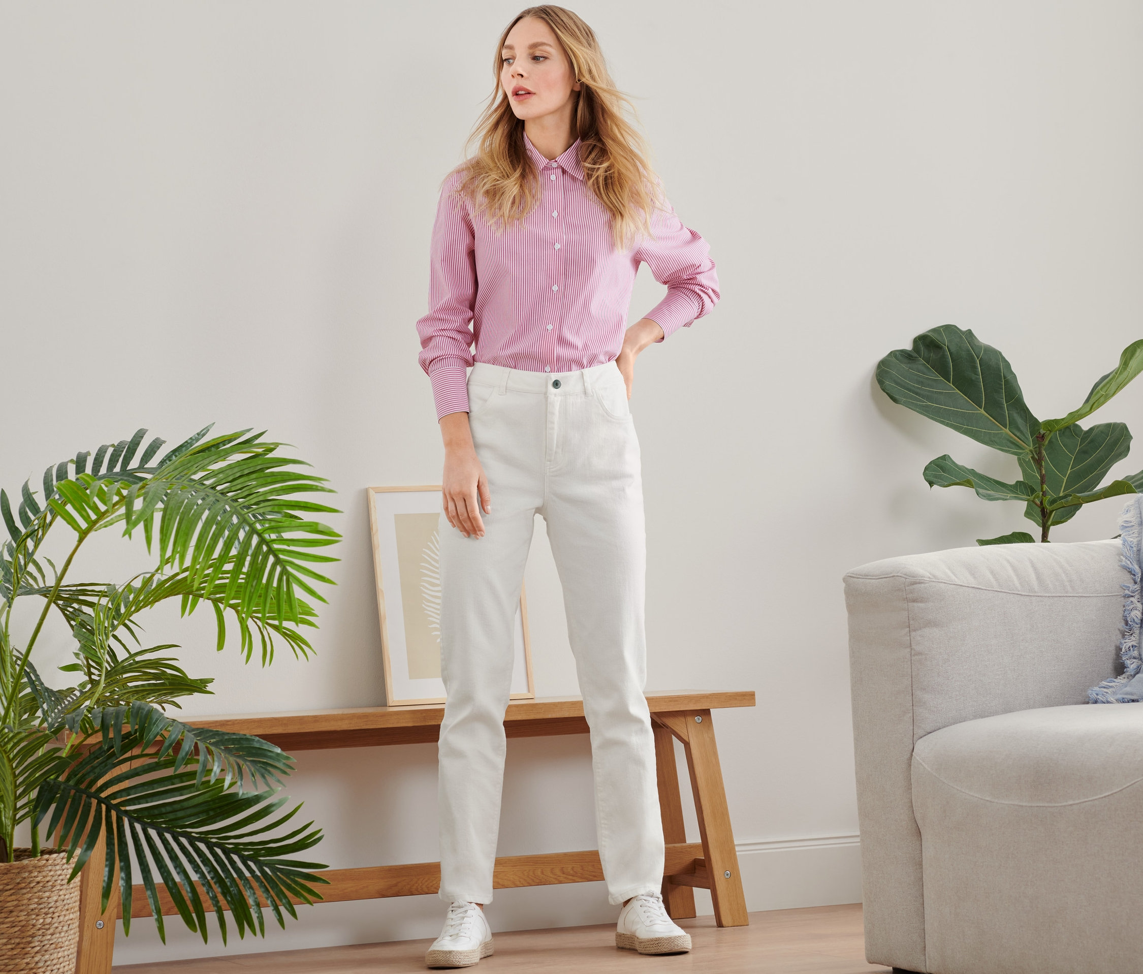 Frau posiert in rosa Hemd und weißen Straightfit-Jeans.