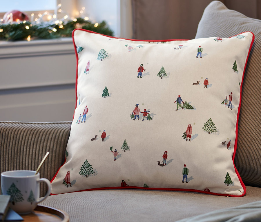 Dekokissen-Bezug mit Winterlandschaftsmotiv liegt auf einem Sofa.