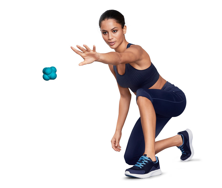 Frau in Sportkleidung wirft türkisfarbenen Massage- und Reaktionsball.