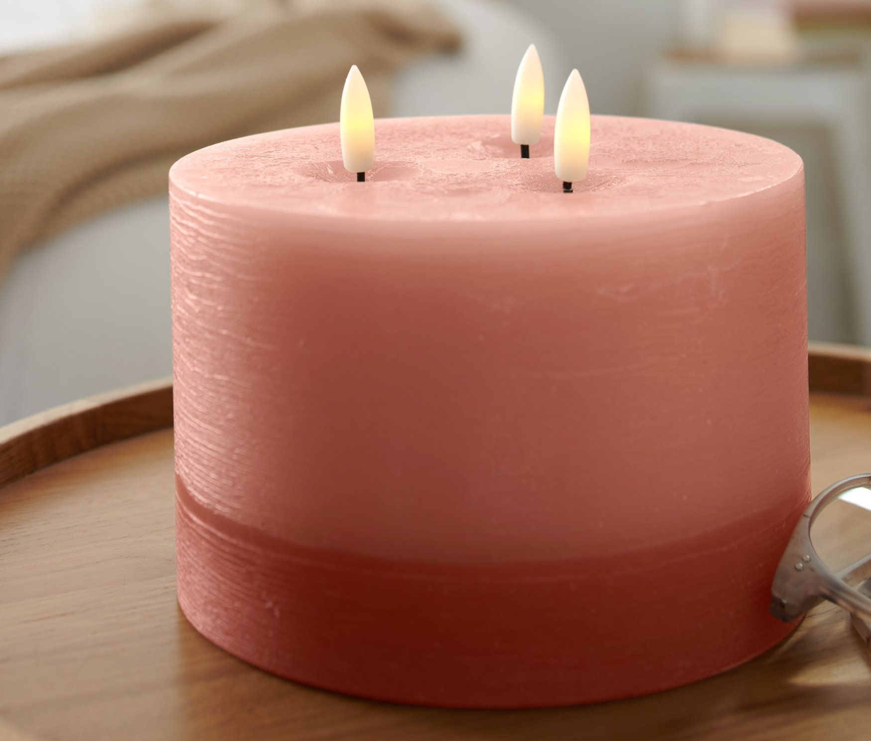 Eine XL LED-Echtwachskerze steht auf einem Holztisch.