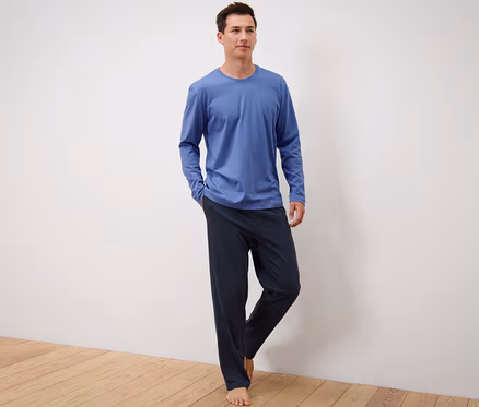 Mann steht und trägt einen blau-dunkelblauen Pyjama.