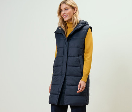 Eine Frau trägt eine lange Steppweste mit Kapuze.