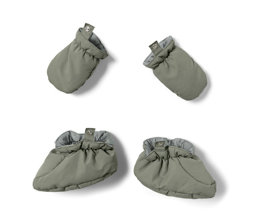 Zwei olivefarbene Baby-Fausthandschuhe und zwei olivefarbene Baby-Schühchen aus Baby-Winteroverall, alle auf weißem Hintergrund.