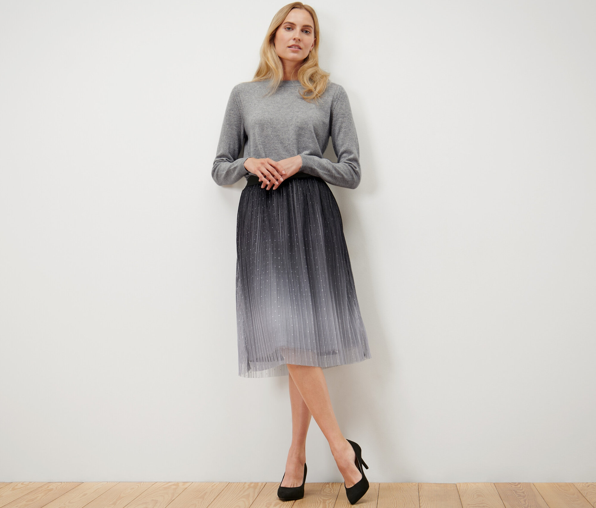 Frau posiert mit einem plissierten Tüllrock mit Farbverlauf.