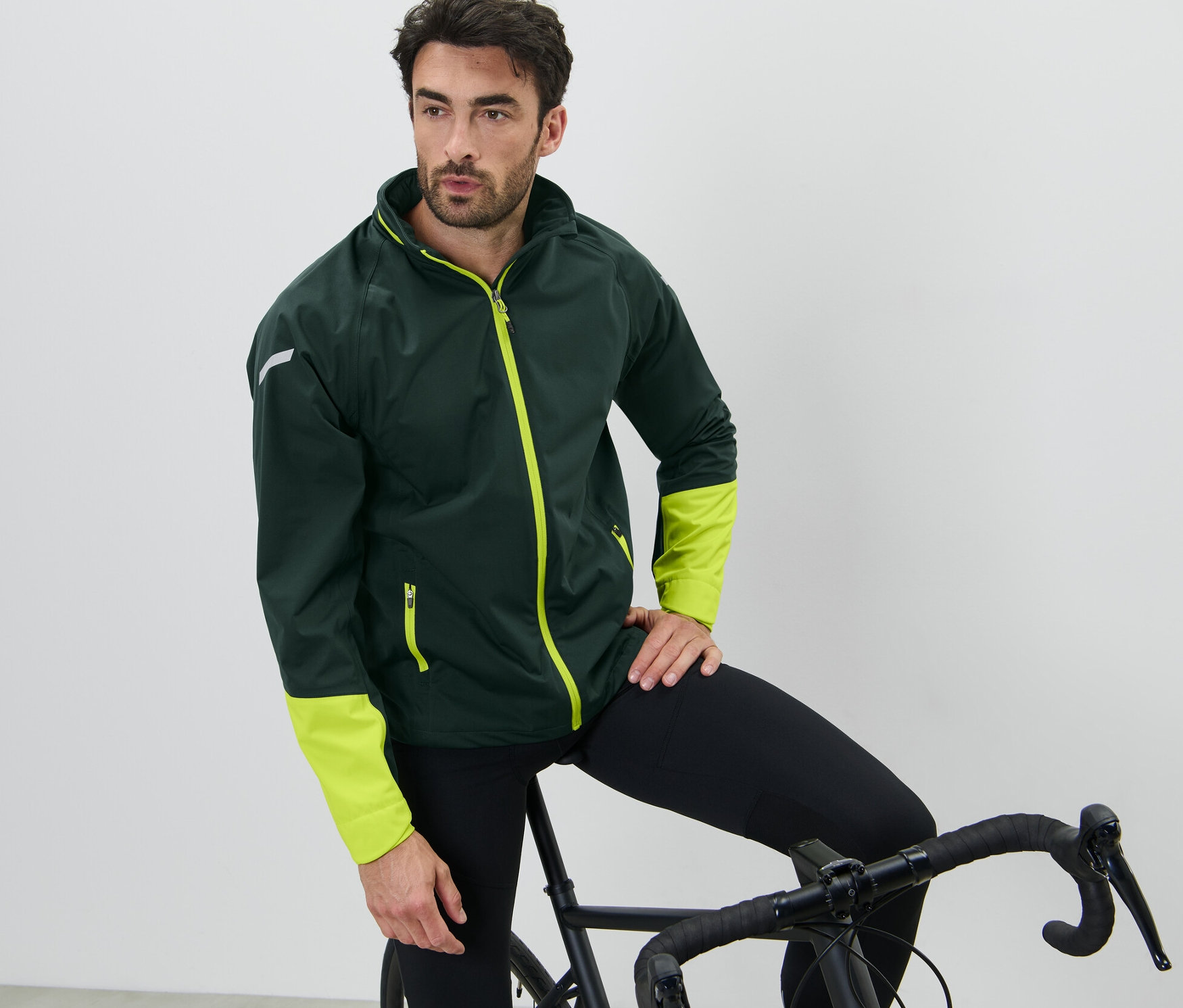 Mann lehnt an Fahrrad, trägt Rad-Regenjacke.