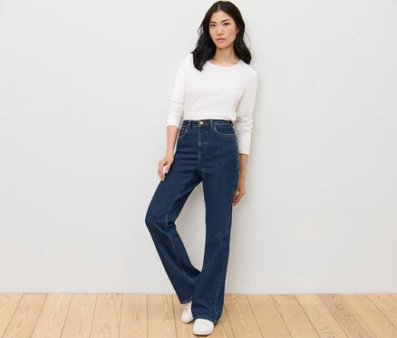 Frau posiert in Bootcut Jeans – Fit »Lou« und weißem Oberteil.