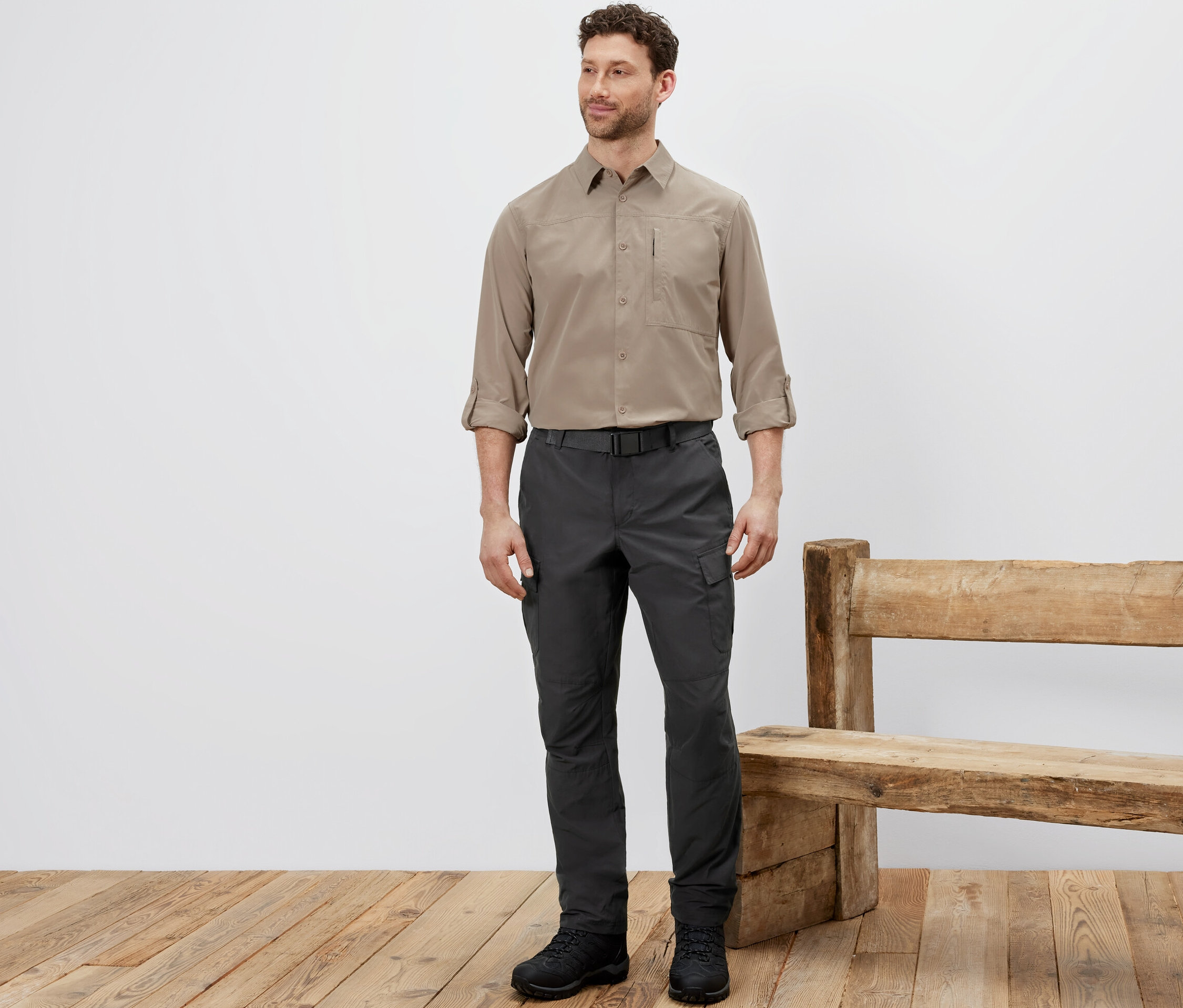 Mann steht in Outdoorhose mit Moskito-Schutz, beigem Hemd und schwarzen Schuhen.