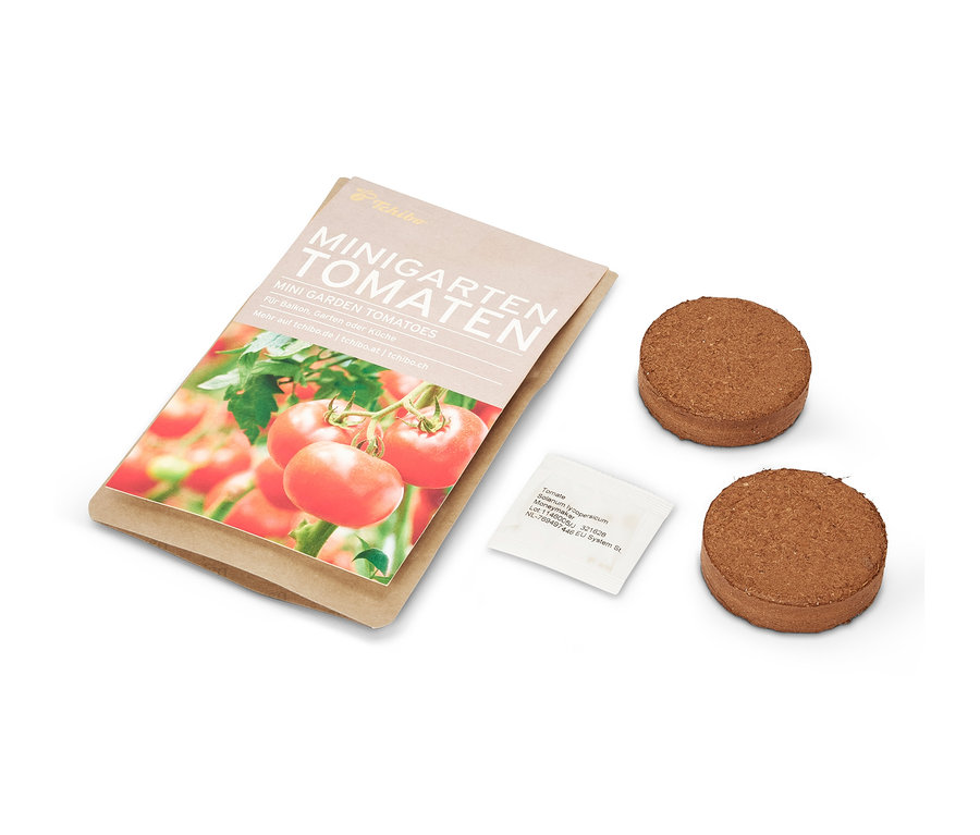 Minigarten in einer Papiertüte mit Tomaten, zwei braune Tabletten und ein Samenpäckchen.