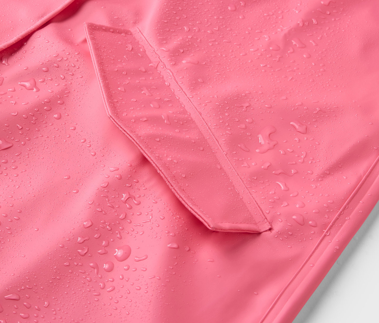 Detailansicht eines rosafarbenen Regenmantels mit Wassertropfen.