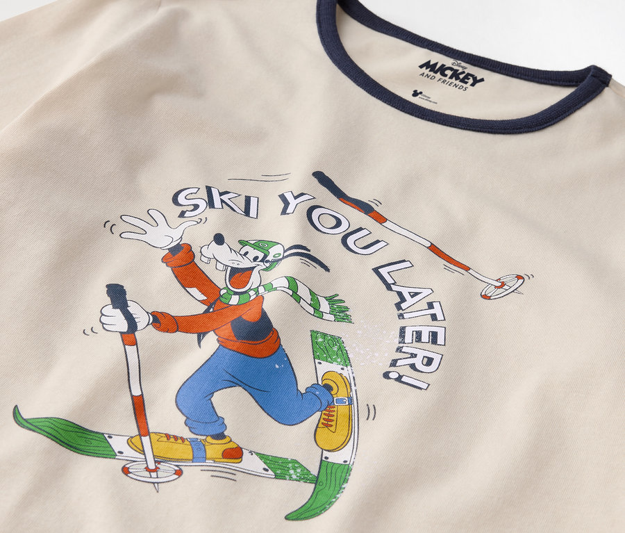 Detail eines Baumwoll-T-Shirts mit Goofy-Print beim Skifahren und dem Spruch "Ski you later!".