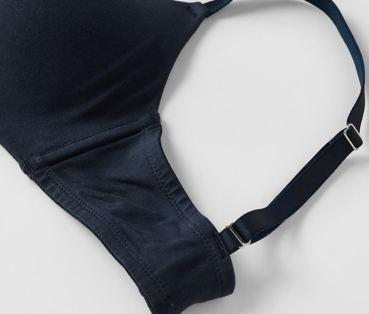 Detailaufnahme eines marineblauen BHs mit verstellbaren Trägern auf weißem Hintergrund.