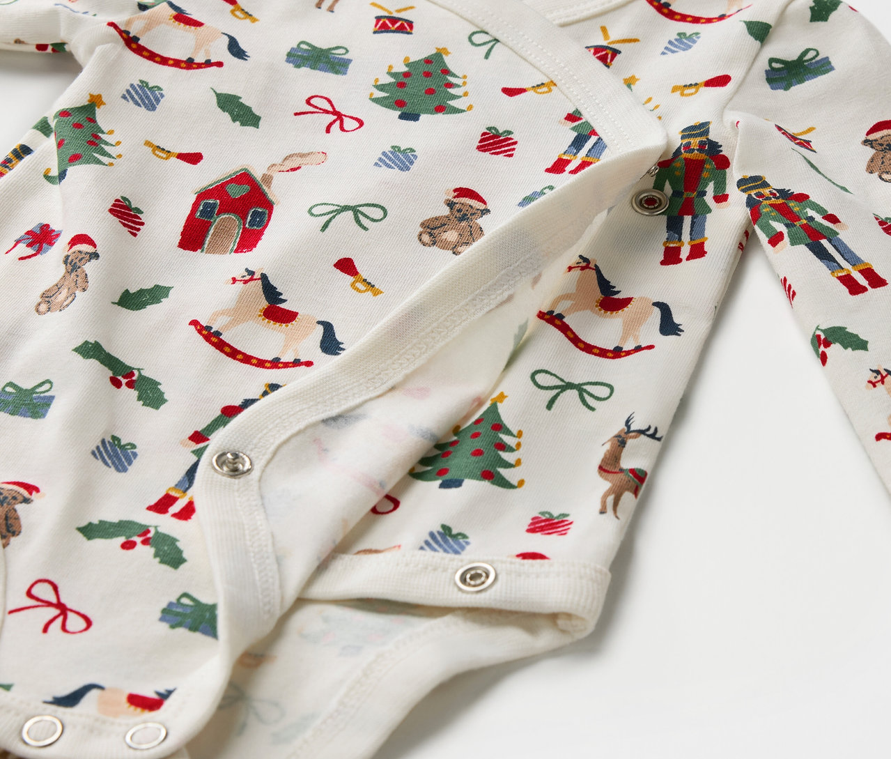 Detail eines Baumwoll-Bodys mit Weihnachtsmotiven und Druckknöpfen.