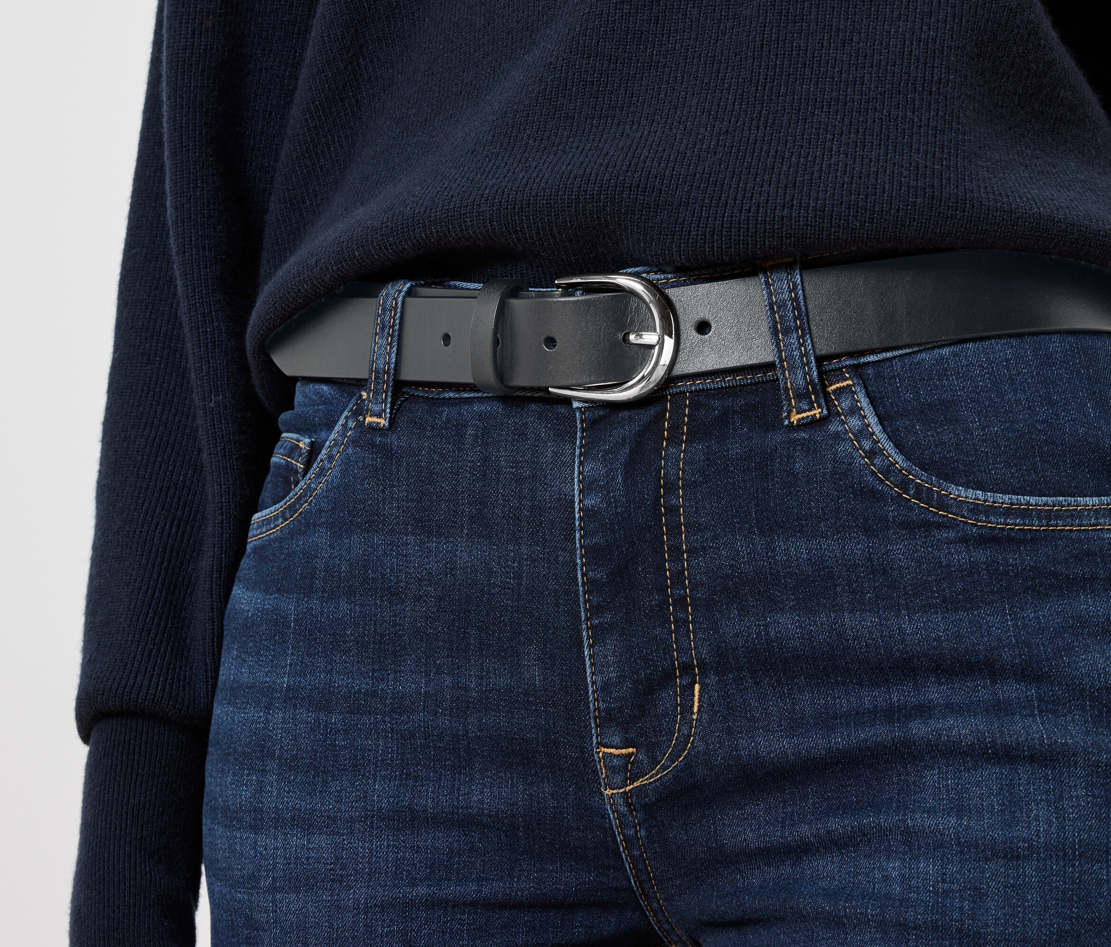 Schwarzer Ledergürtel auf blauen Jeans.