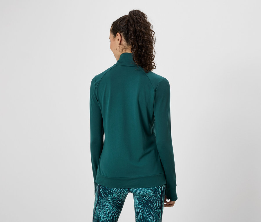Frau von hinten in grüner Trainingsjacke und gemusterter Leggings vor weißem Hintergrund.
