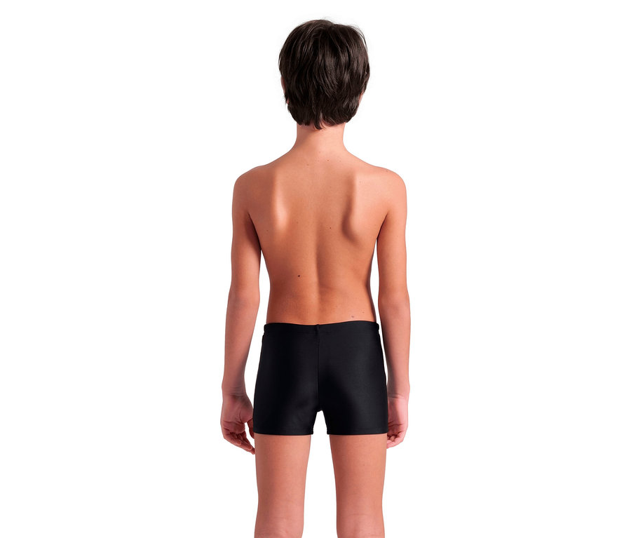 Rückansicht eines Kindes mit kurzen braunen Haaren, das eine schwarze Badehose trägt.