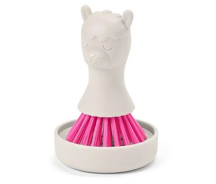 Eine graue Bürste mit rosa Borsten steht in einer grauen Halterung. Der Griff hat die Form eines Lamas.