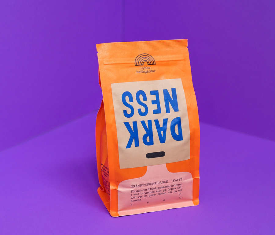 Orangefarbene Packung Lykke kaffegårdar Dark Ness Kaffee steht vor einer lila Ecke.