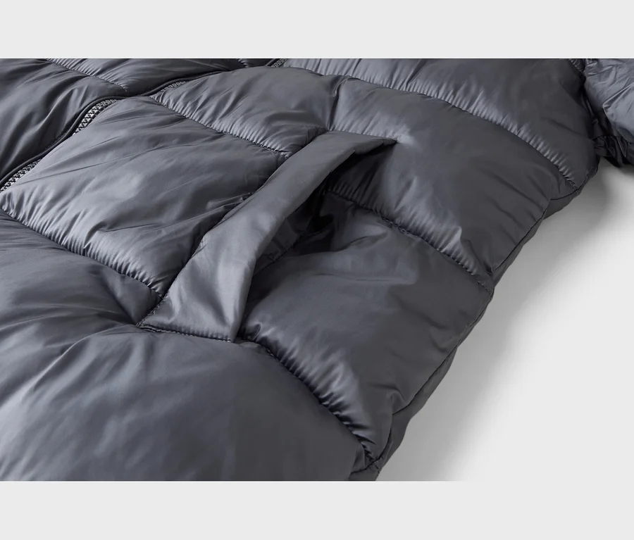 Nahaufnahme einer dunkelgrauen, glänzenden Steppjacke mit einer sichtbaren Seitentasche und Reißverschluss.