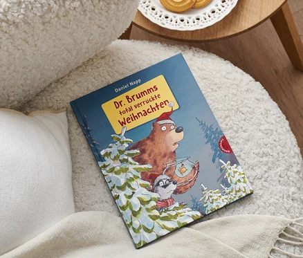 Das Buch »Dr. Brumms total verrückte Weihnachten« liegt auf einem Sessel neben einem Kissen.