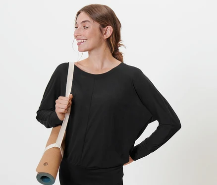 Frau mit Yogamatte über der Schulter, trägt ein schwarzes Sport-und-Yogashirt.