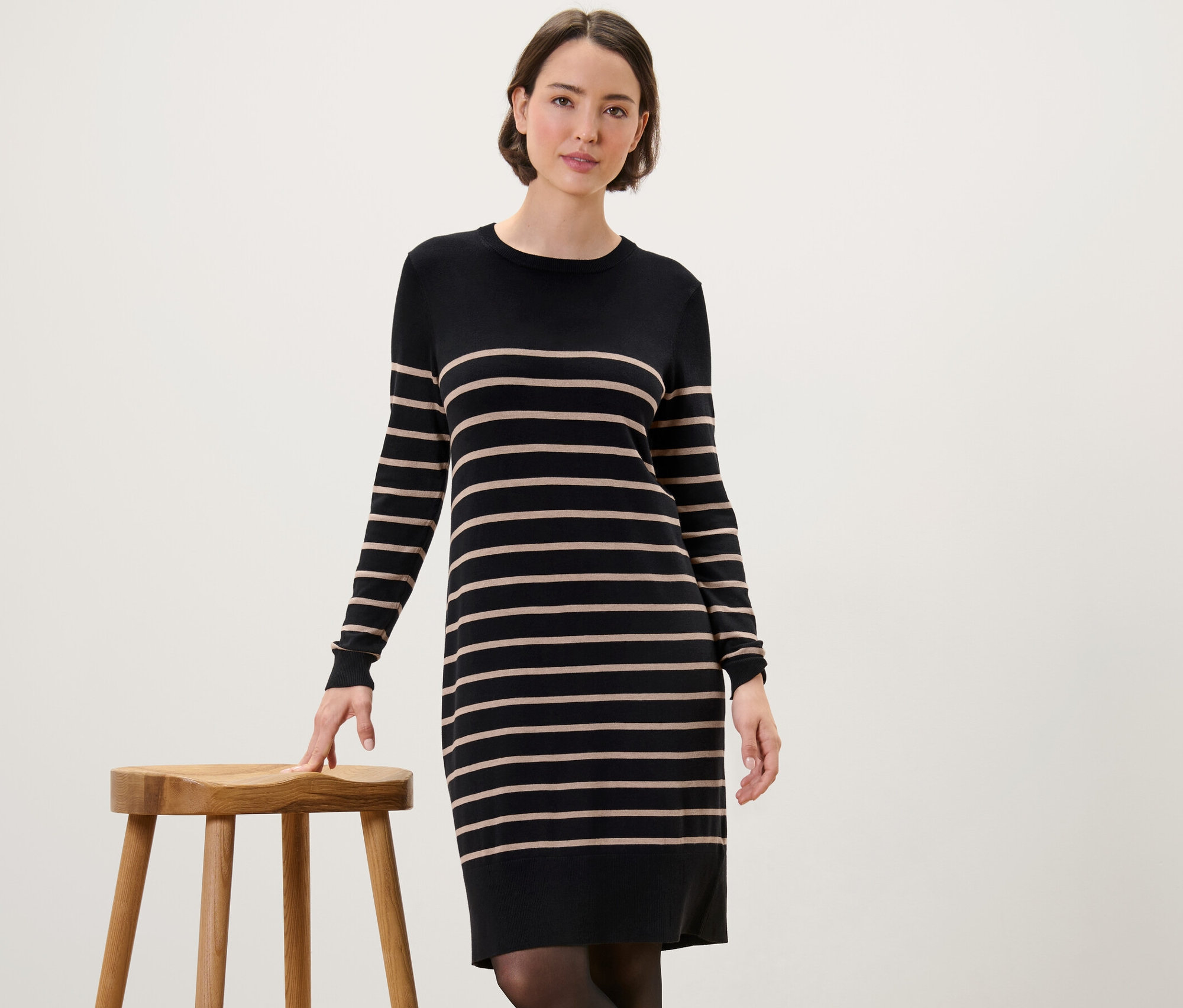 Frau posiert in einem gestreiften Feinstrickkleid.