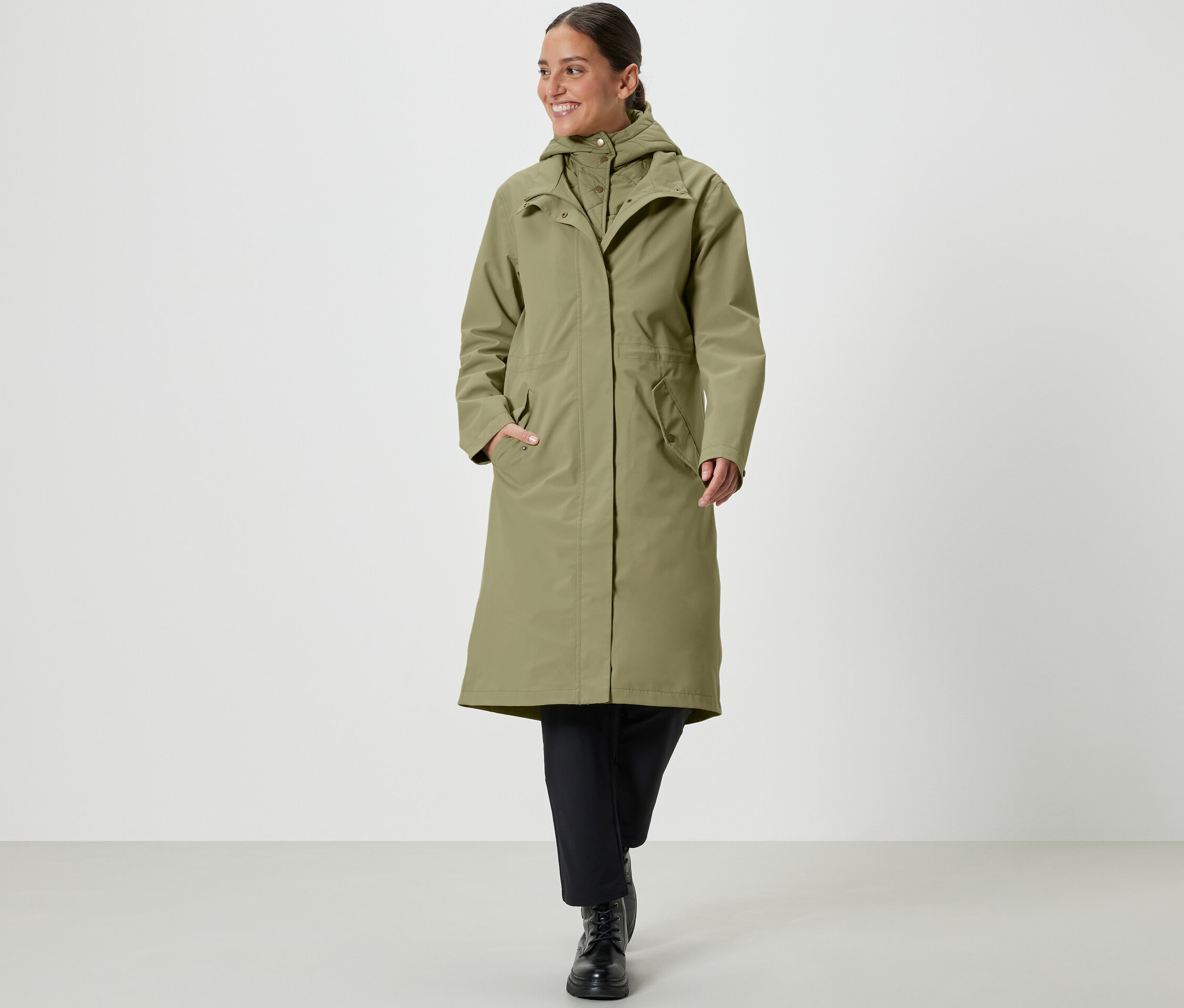 Frau geht und trägt einen khakifarbenen Regenmantel.