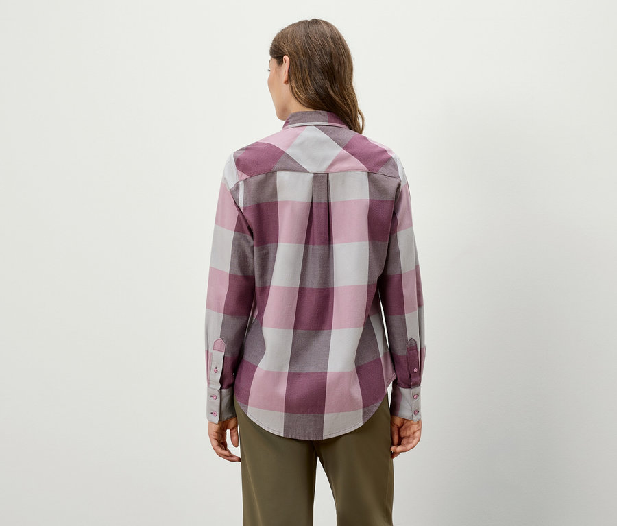 Von hinten ist eine Frau in einem langärmeligen karierten Hemd und einer grünen Hose zu sehen.