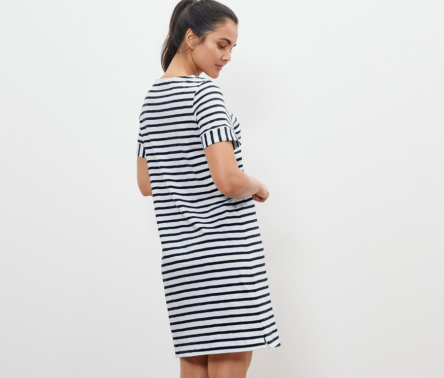 Frau posiert in einem gestreiften Jerseykleid.