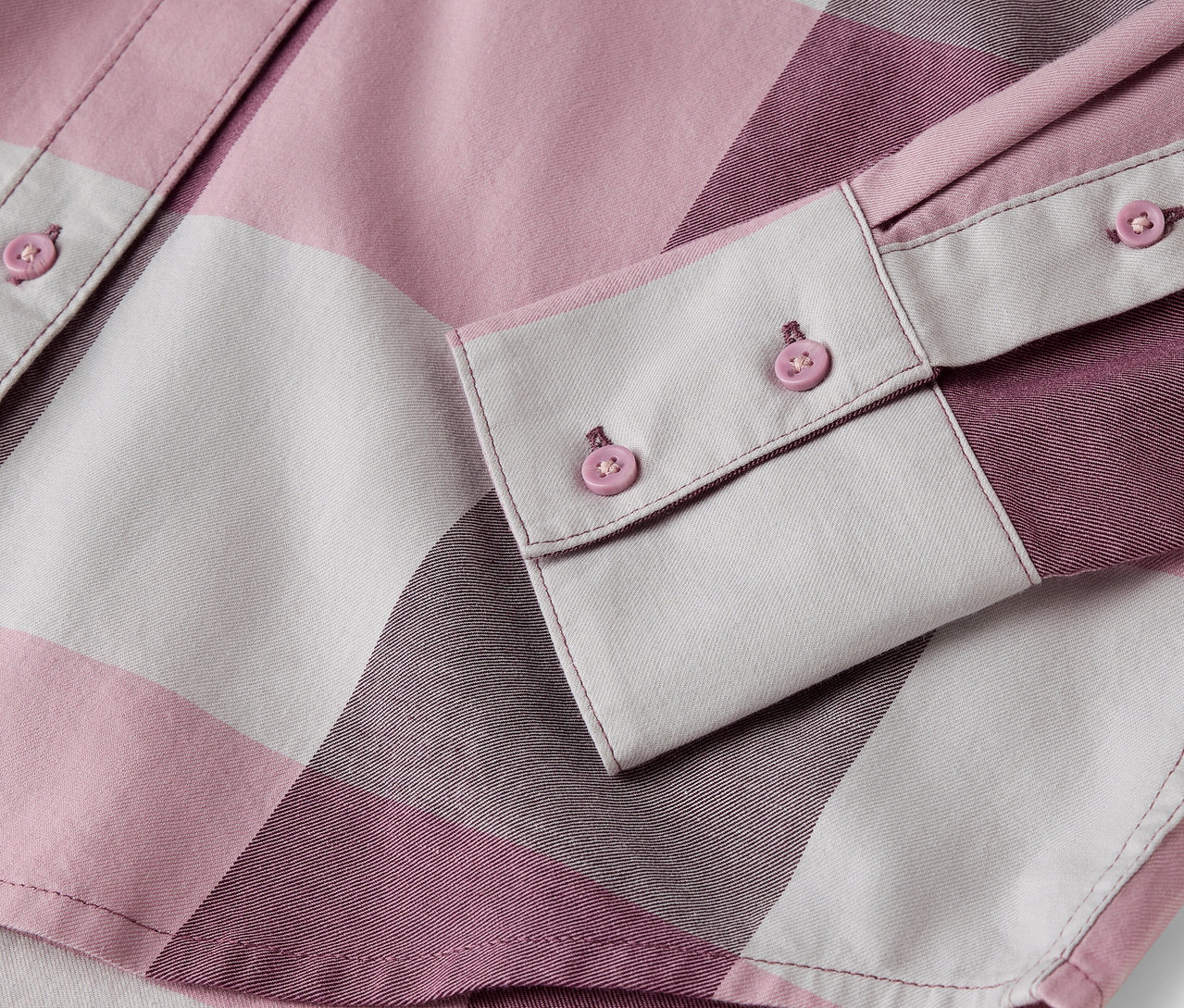 Detail eines rosa-weiß karierten Hemdes mit Knöpfen.