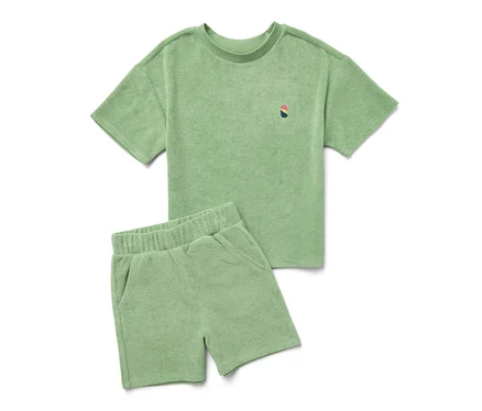 Ein grünes Kinder-Frottier-Set aus T-Shirt und Shorts liegt auf einem weißen Hintergrund.