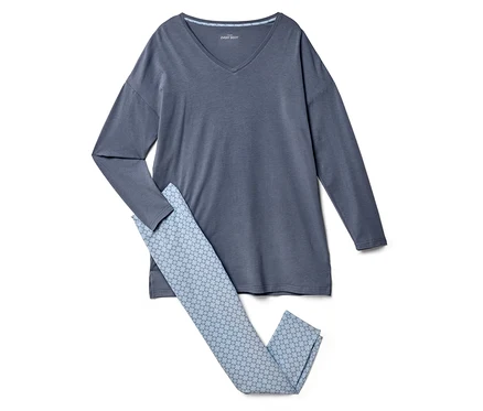 Ein graues langärmliges Shirt liegt neben einer hellblauen Hose mit geometrischem Muster.