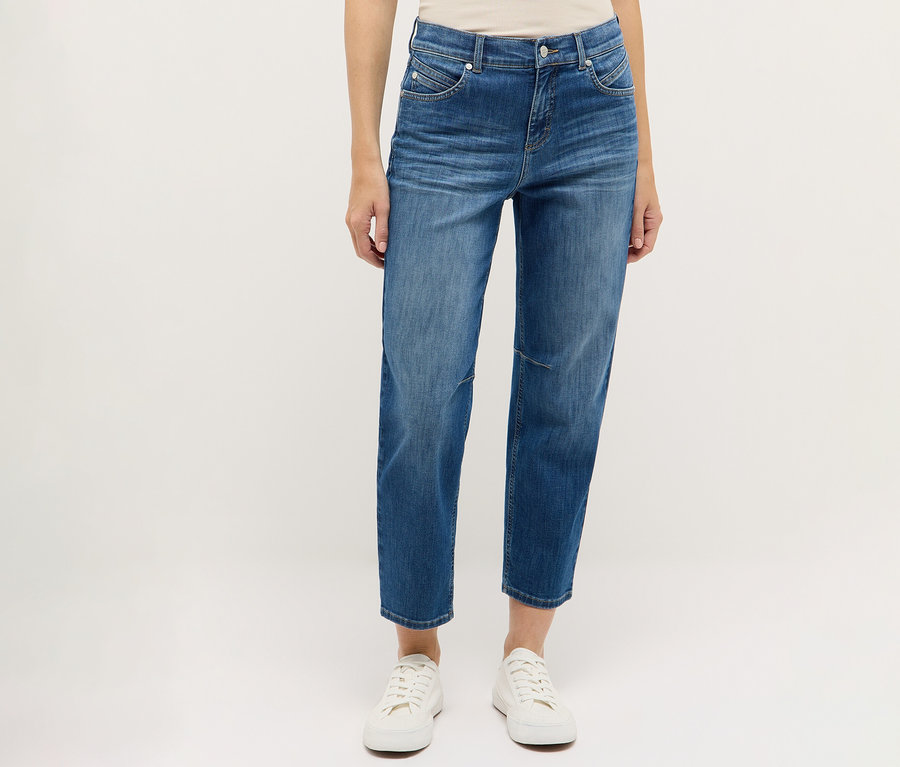 Person trägt blaue Angels Denim »Evi« Jeans und weiße Schuhe vor einem weißen Hintergrund.