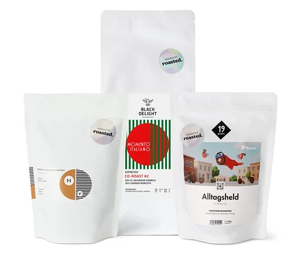 Vier Packungen Kaffeebohnen unterschiedlicher Röstungen stehen nebeneinander.
