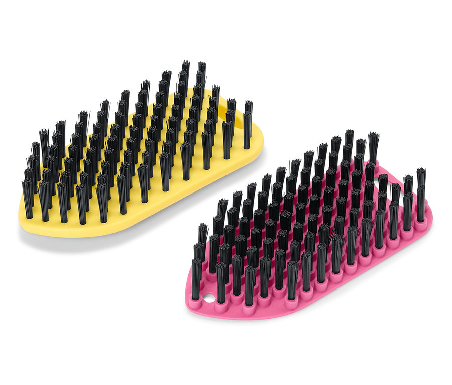Zwei Bürsten liegen auf weißem Grund, eine gelbe und eine pinke, beide mit schwarzen Borsten.