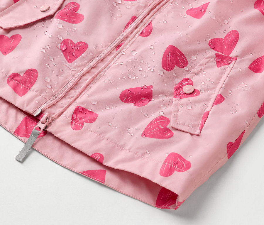 Nahaufnahme einer rosa Regenjacke mit Herzmuster und Wassertropfen.