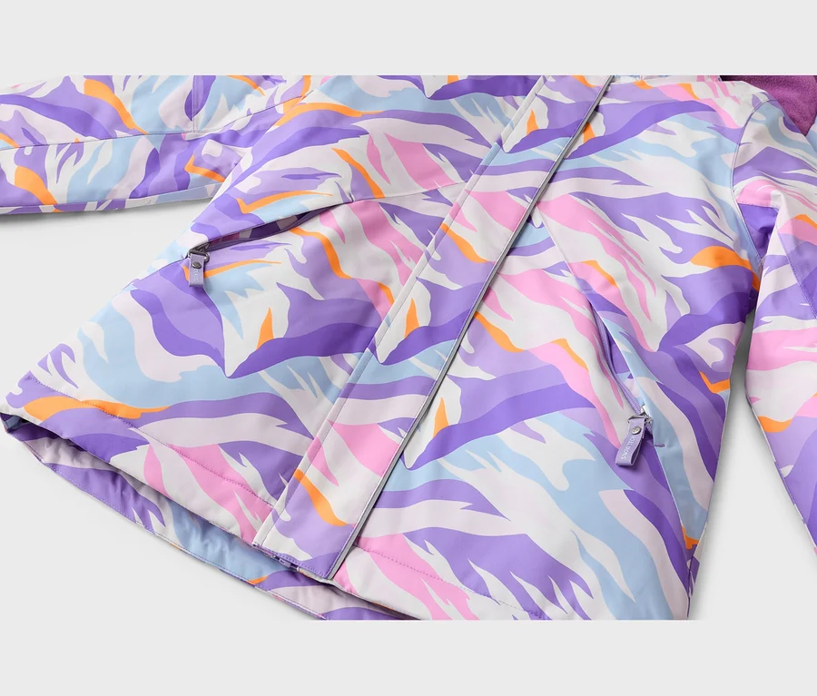 Nahaufnahme einer Jacke mit einem abstrakten, bunten Muster in Lila, Pink, Hellblau, Orange und Weiß. Zwei Reißverschluss-Taschen und eine zentrale Reißverschlussleiste sind sichtbar, oben rechts ist eine lila Kapuze teilweise zu sehen.