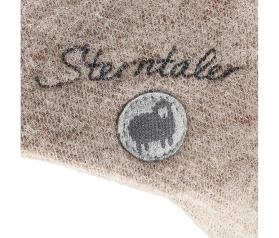 Beiger, flauschiger Stoff mit gesticktem "Sterntaler"-Schriftzug und einem runden grauen Aufnäher mit Schaf-Silhouette.
