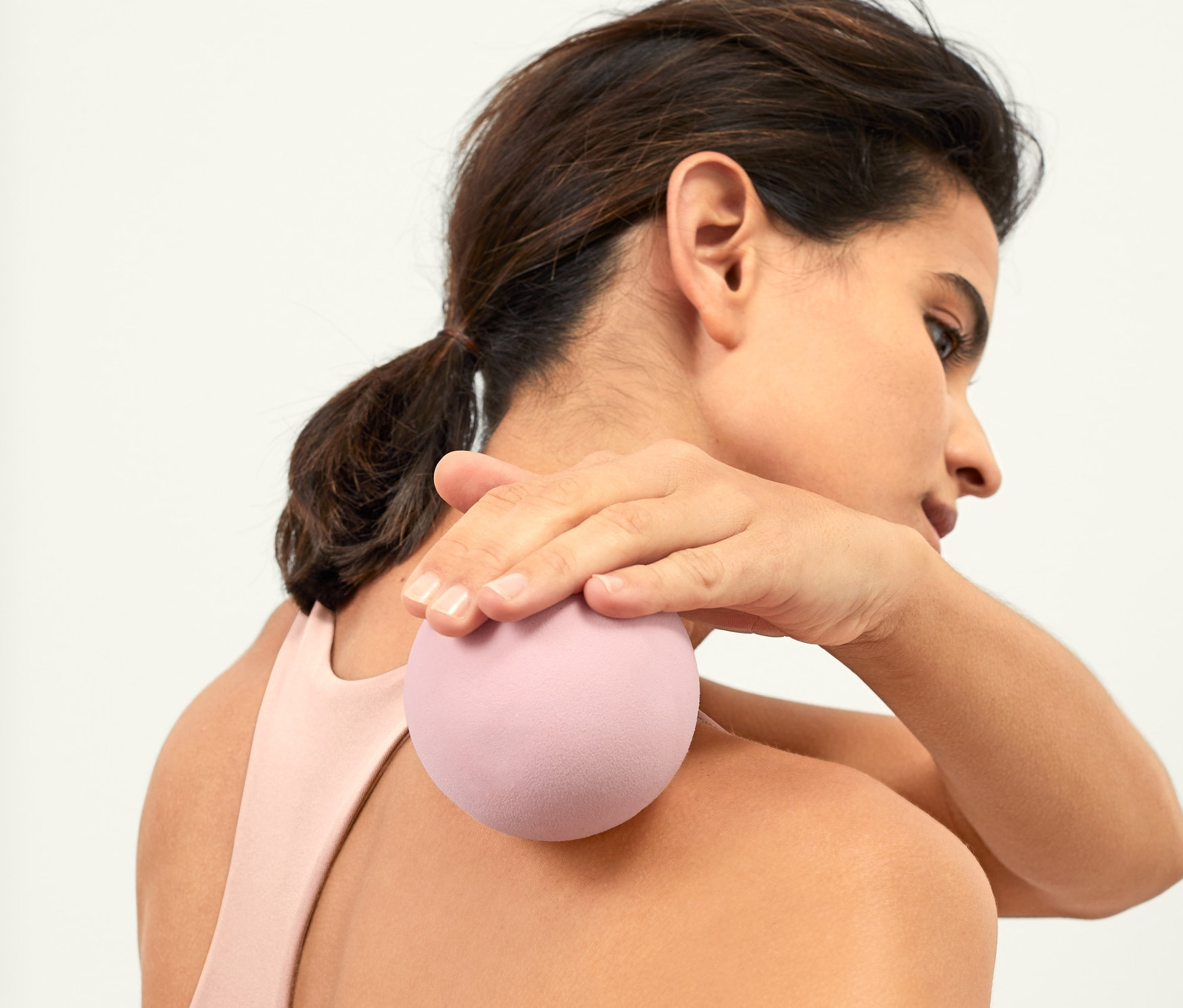 Frau massiert oberen RĂŒcken mit Faszienball.