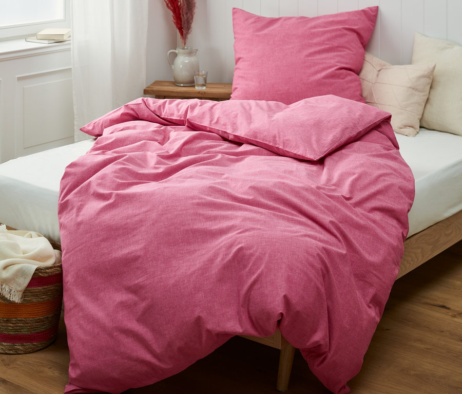 Rosa Renforcé-Bettwäsche in verschiedenen Größen auf einem Bett.