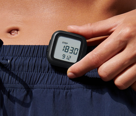 Frau hält Schrittzähler in der Hand.