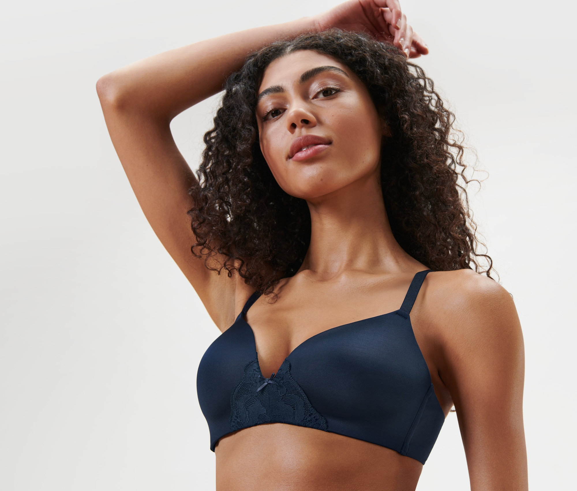 Frau mit einer Hand über dem Kopf trägt einen blauen Softschalen-BH.
