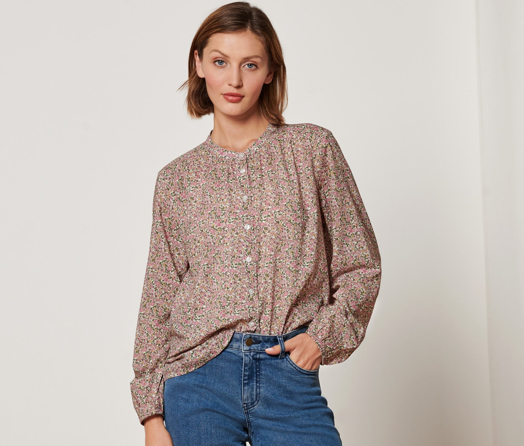 Frau trägt eine florale Bluse und Jeans.