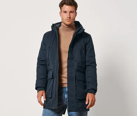Ein Mann steht und trägt eine navyblaue Parka.