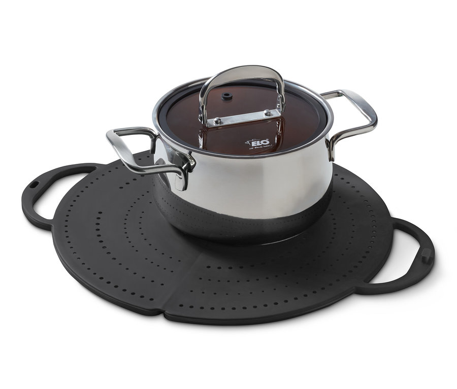 Ein Edelstahltopf mit Deckel steht auf einem schwarzen Pfannenspritzschutz.