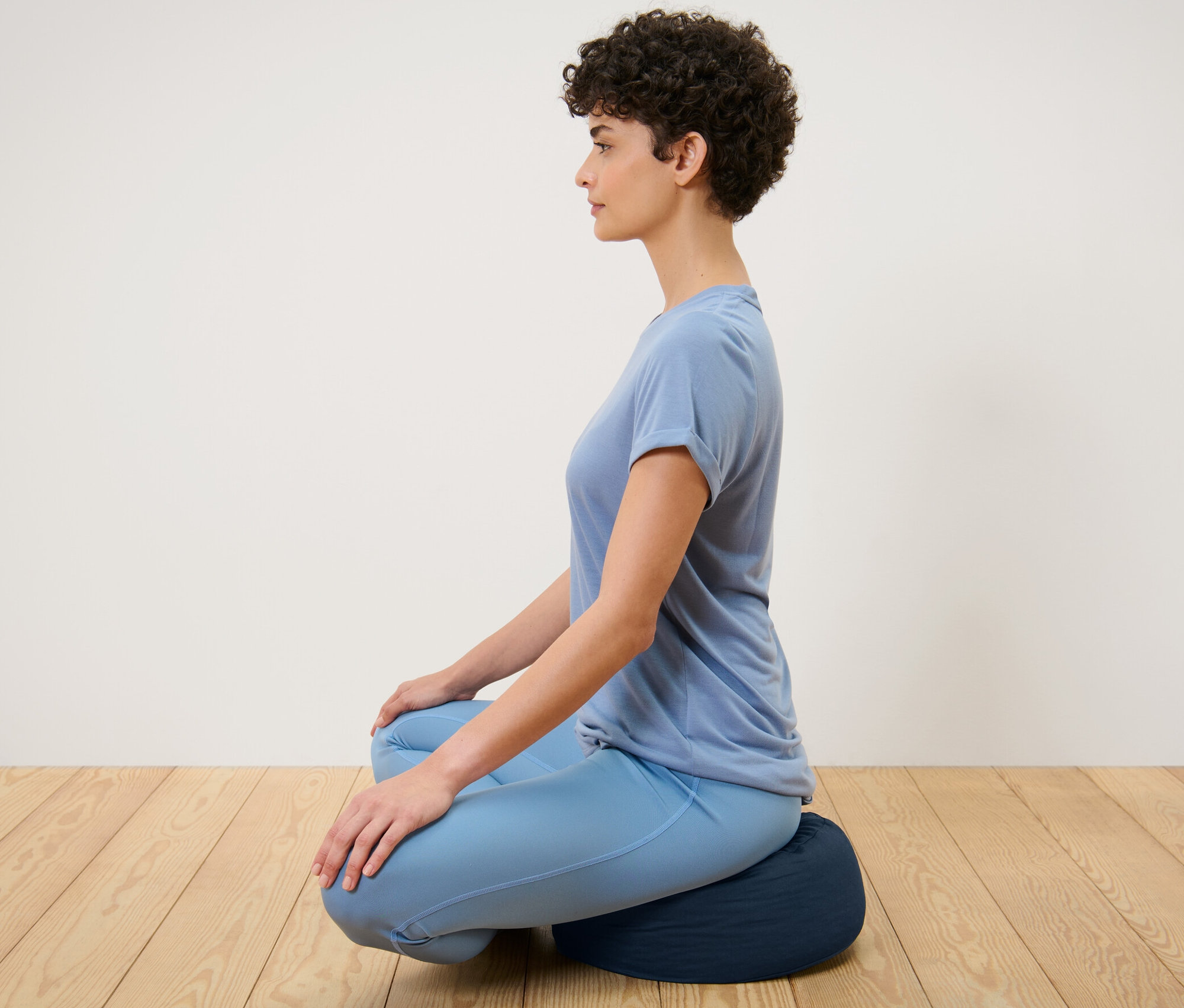 Frau sitzt auf einem Meditationskissen.