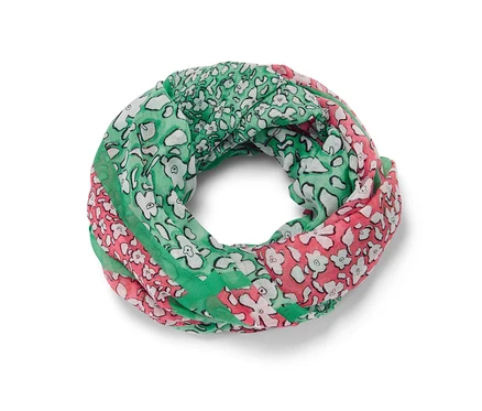 Ein bedruckter Loop-Schal in Grün, Rosa und Weiss liegt.